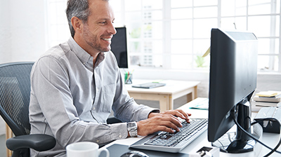 A man smiling while working on a desktop computer