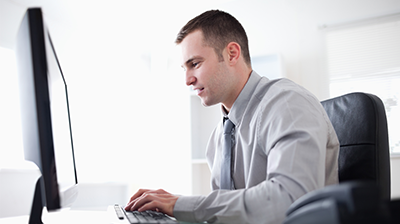 Man in business attire sitting at desk and typing on computer