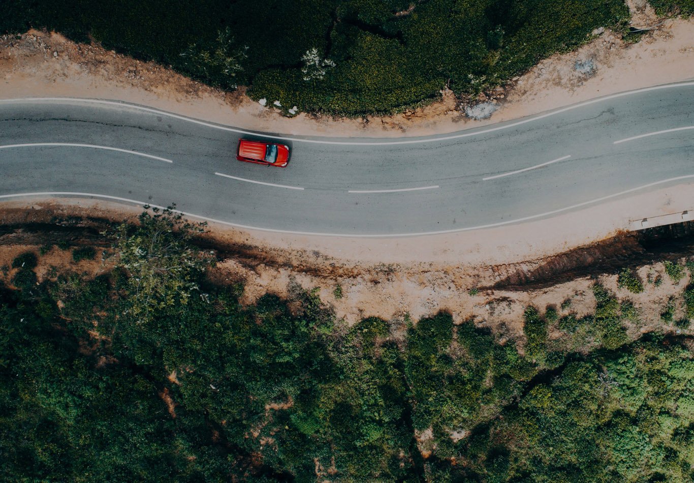 A single car is driving on a winding road. 